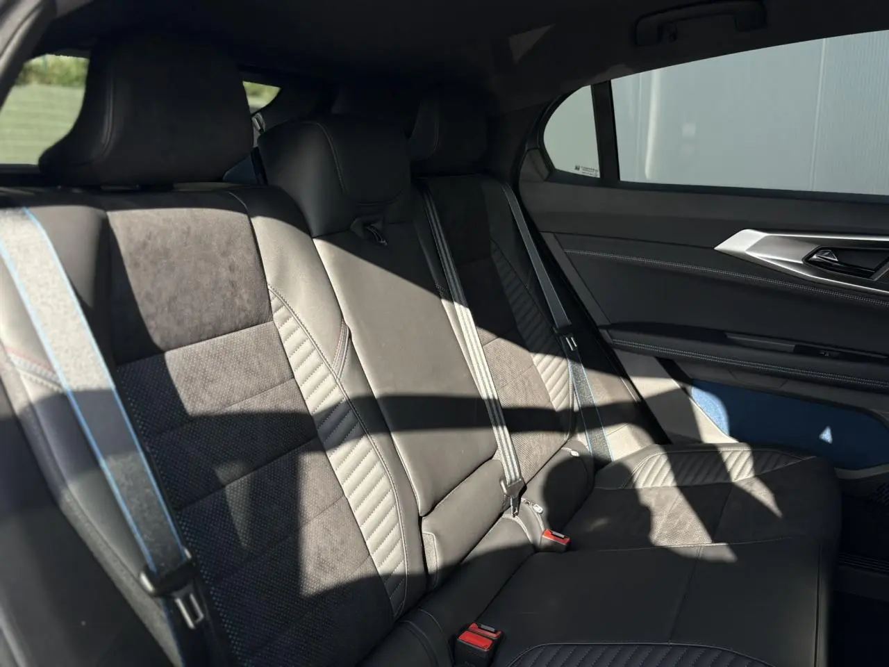 Banquette arrière en cuir et textile gris avec surpiqûres bleu, blanc, rouge dans une Renault Rafale E-Tech 2025.