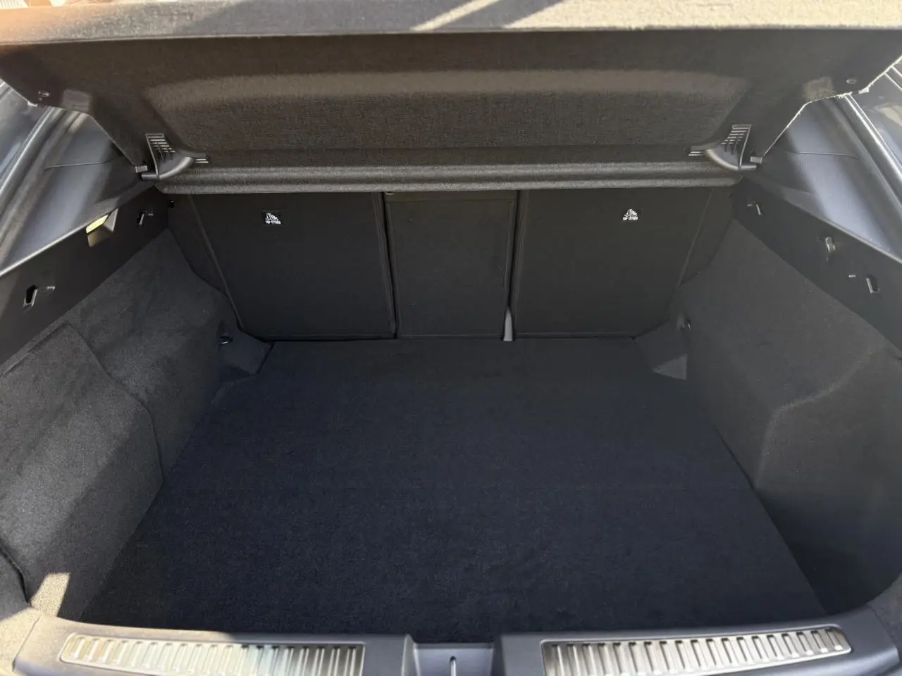 Coffre ouvert vu de l'arrière d'une Renault Rafale gris schiste, montrant l'espace de chargement vide et tapis noir.