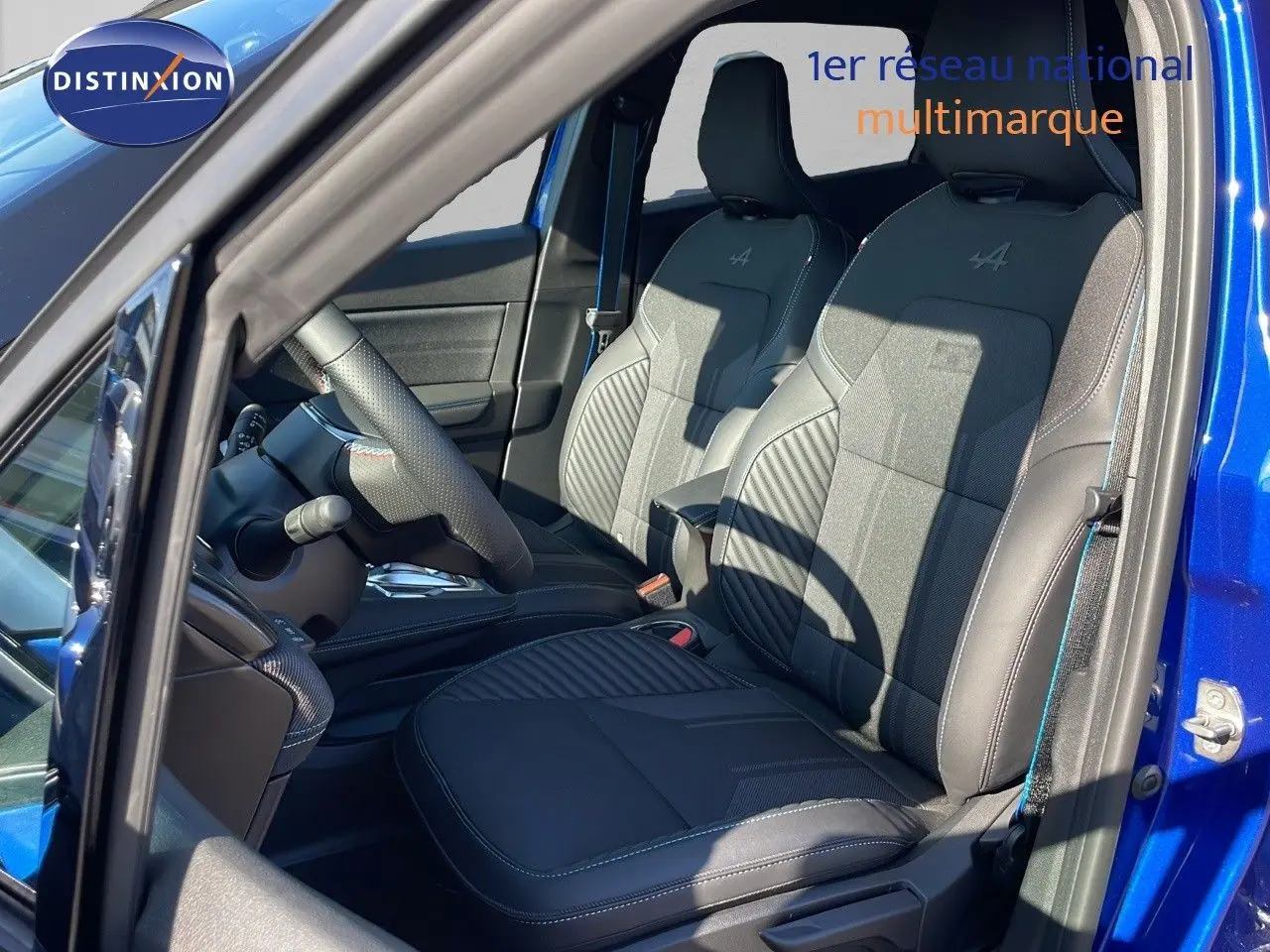Vue intérieure côté conducteur du Renault Captur E-Tech hybride 2025 avec sièges noirs Alpine et détails bleus.