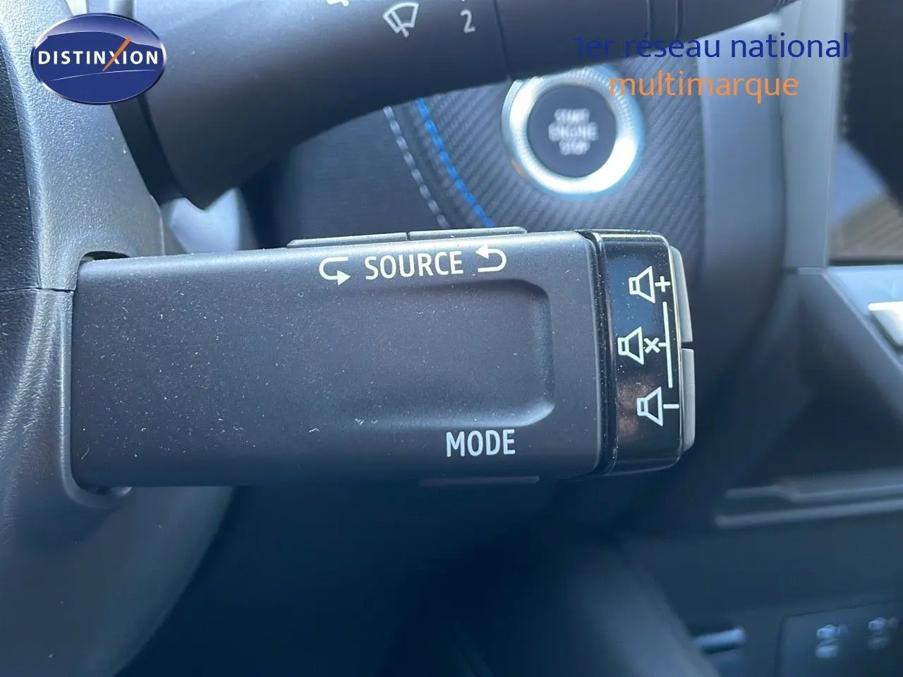 Commande au volant pour source audio et mode sur Renault Captur E-Tech Hybrid 2025, intérieur noir avec surpiqûres bleues.