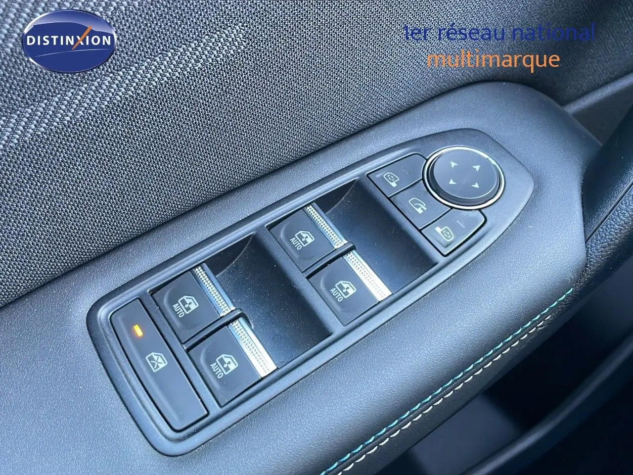Gros plan sur les commandes des vitres électriques côté conducteur du Renault Captur E-Tech hybride 2025 avec surpiqûres bleues.