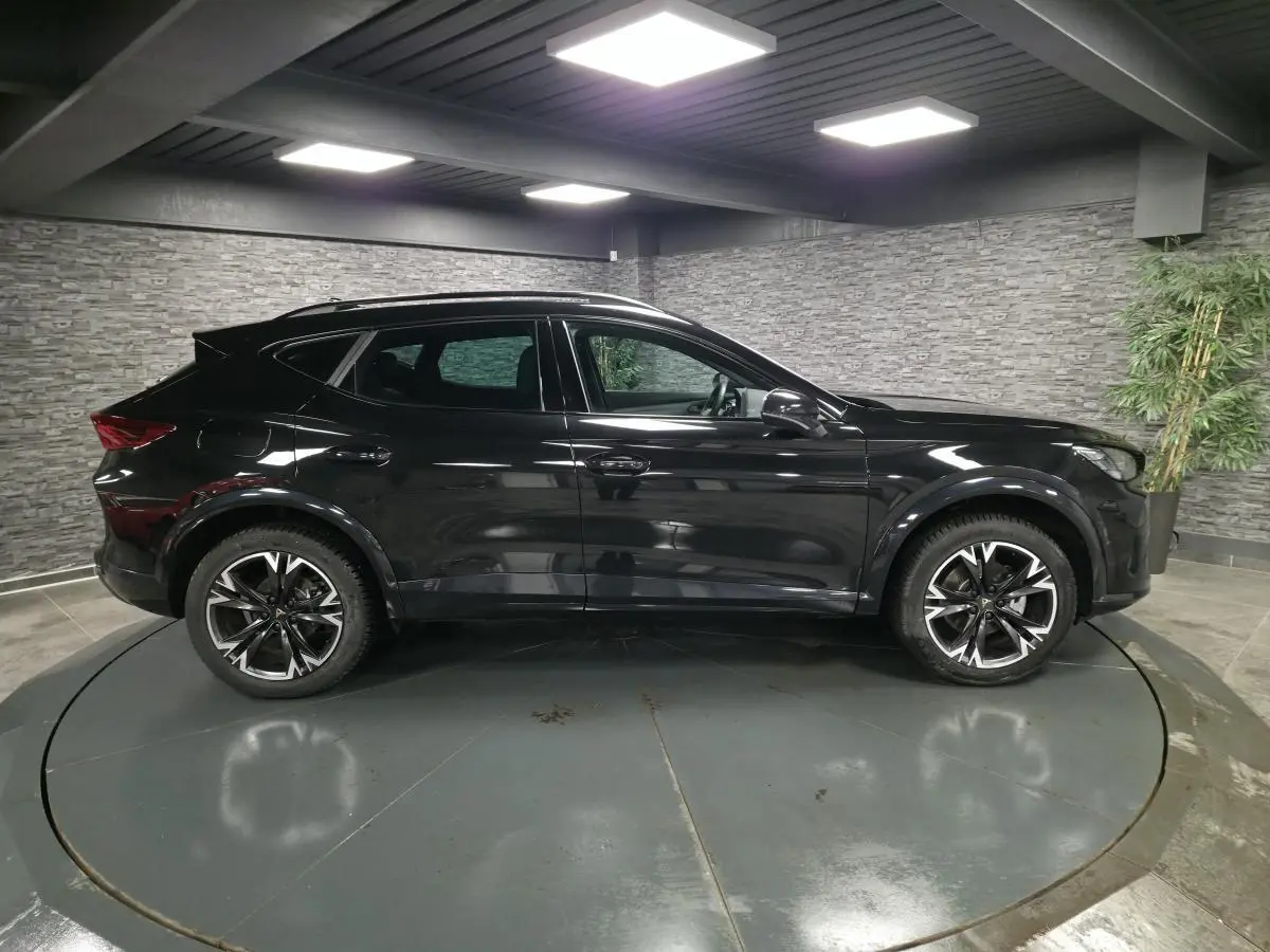 Profil droit du CUPRA Formentor noir avec jantes alliage 18'' usinées dans un showroom intérieur.