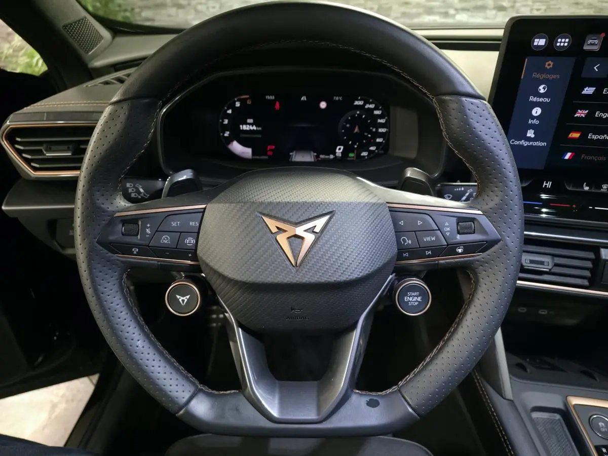 Vue rapprochée du volant noir perforé du CUPRA Formentor 2025 avec logo cuivré et commandes intégrées.