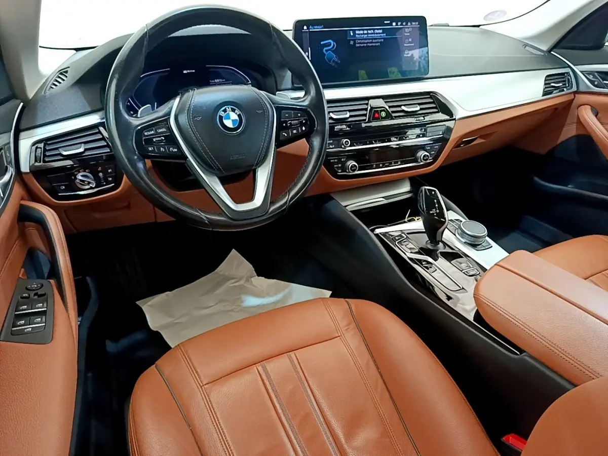 Intérieur BMW Série 5 Touring 530e 2022, vue cockpit côté conducteur, cuir marron et tableau de bord digital.