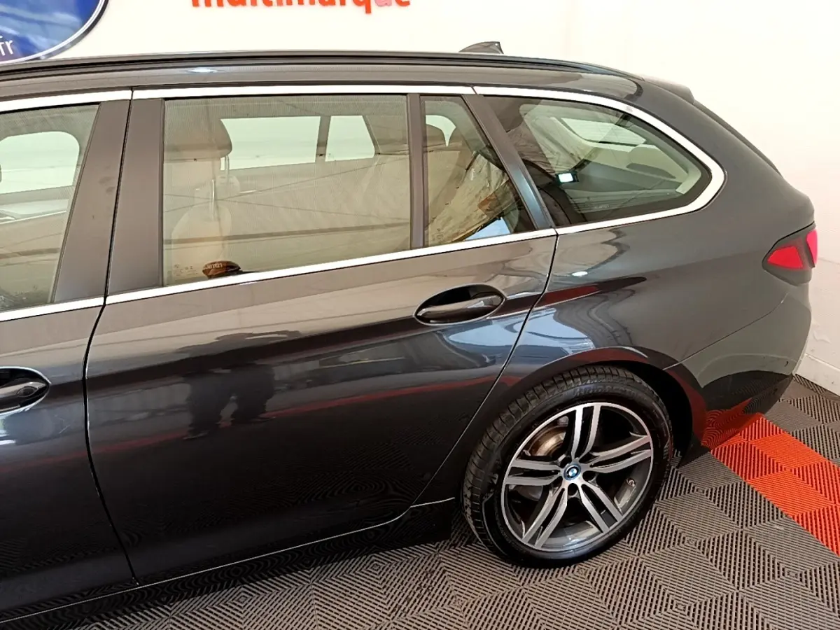Vue latérale côté droit sur l'arrière d'une BMW Série 5 Touring 530e gris clair avec jante alliage distinctive.