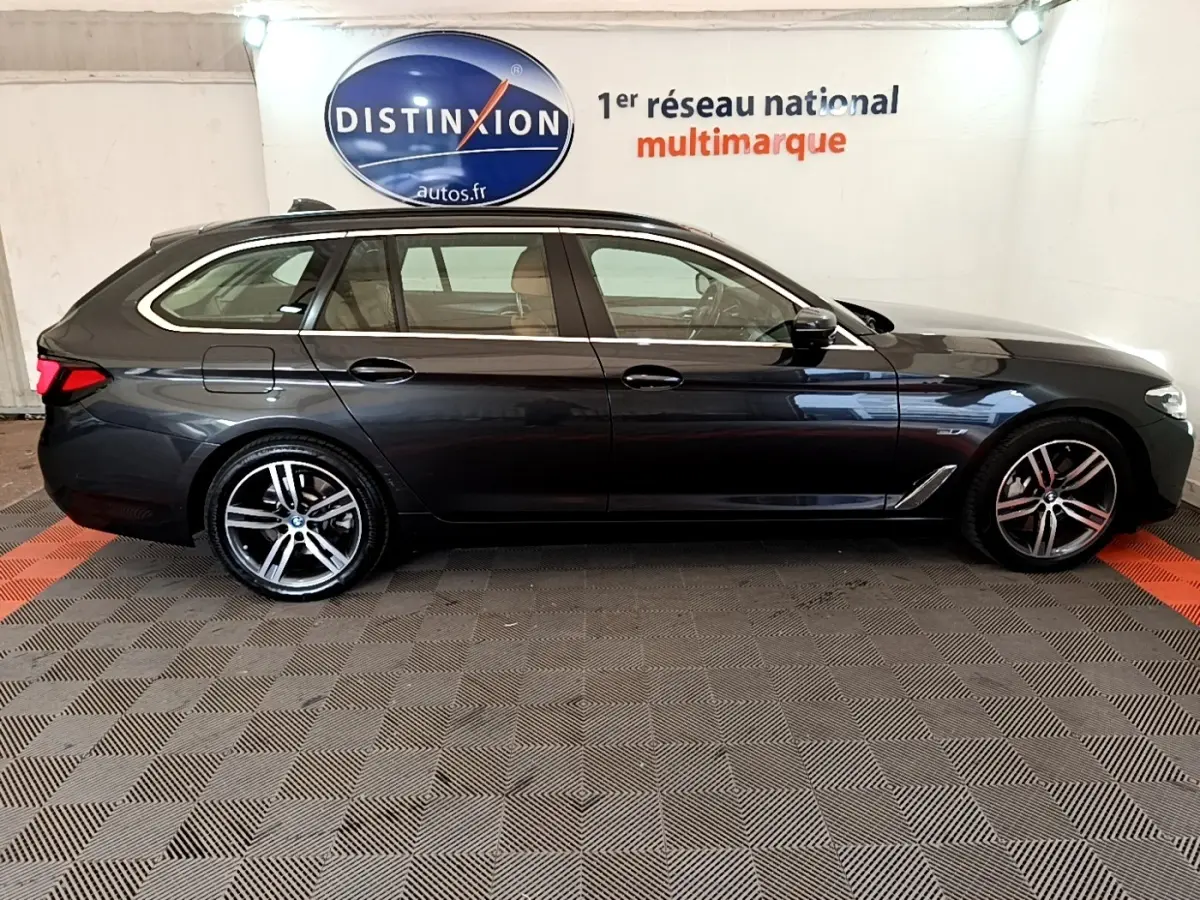 BMW Série 5 Touring 530e gris clair vue de profil côté gauche, avec jantes alliage et toit ouvrant visible.