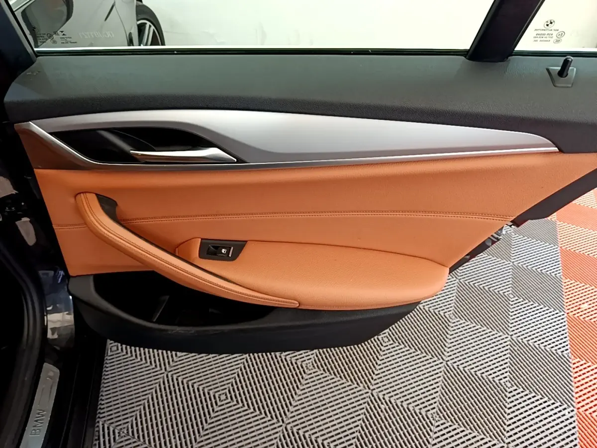 Gros plan sur la porte intérieure côté gauche de la BMW Série 5 Touring 530e 2022, garniture cuir marron clair et insert aluminium.