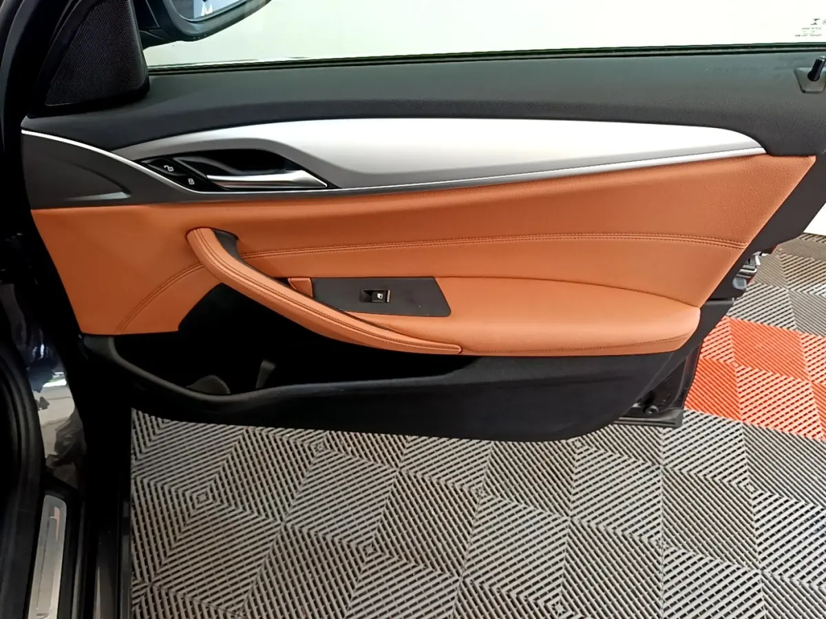 Vue côté gauche de la porte intérieure cuir marron clair et garnitures noires d'une BMW Série 5 Touring 530e 2022.