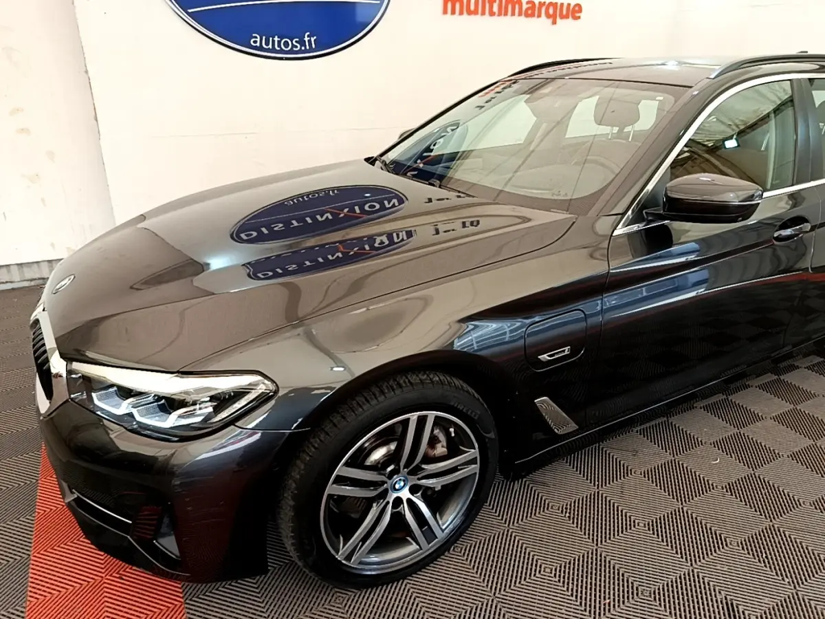 BMW Série 5 Touring 530e gris clair vue 3/4 avant droit, mettant en valeur les jantes alliage et les phares LED.