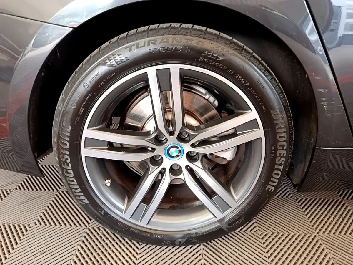 Gros plan sur la roue avant droite grise d'une BMW Série 5 Touring 530e avec jante alliage et logo BMW central.