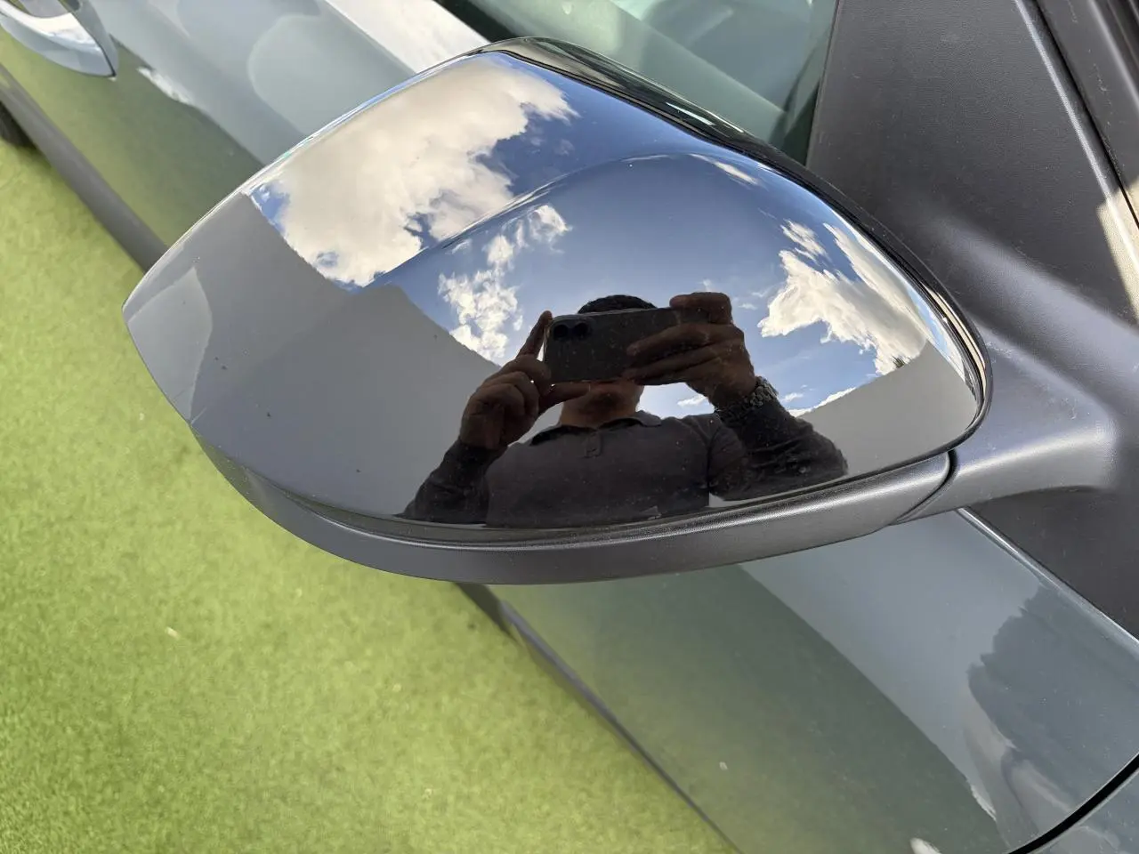 Rétroviseur extérieur droit noir brillant sur Citroën C5 Aircross vert Astoria avec reflet du ciel et d'une personne.