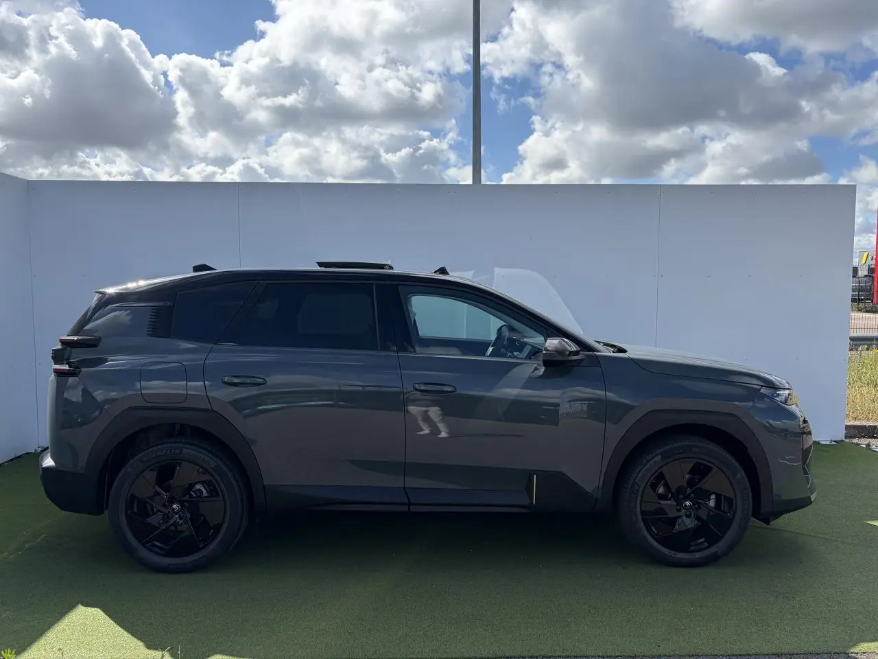 Vue latérale droite d'un Citroën C5 Aircross 2026 gris foncé avec toit noir et jantes noires brillantes.