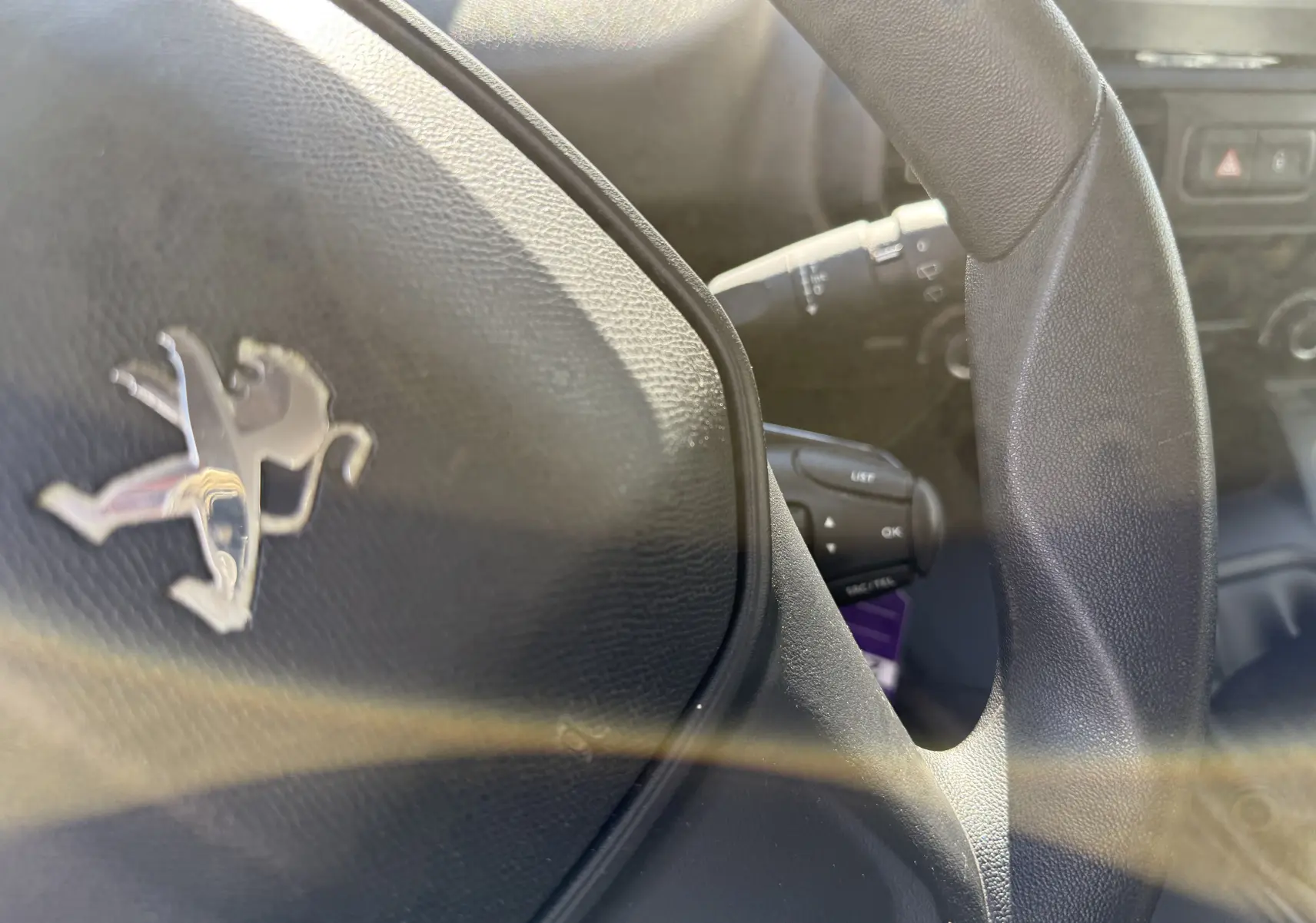 Gros plan sur le volant noir du Peugeot Rifter Diesel 2019, mettant en valeur le logo lion chromé au centre.