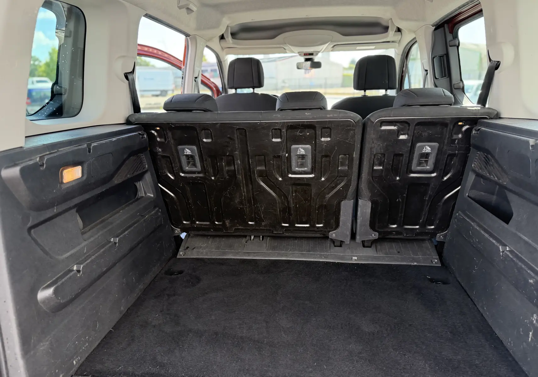 Vue intérieure depuis le coffre du Peugeot Rifter Copper Metallic, montrant les sièges arrière relevés et l’espace de chargement.