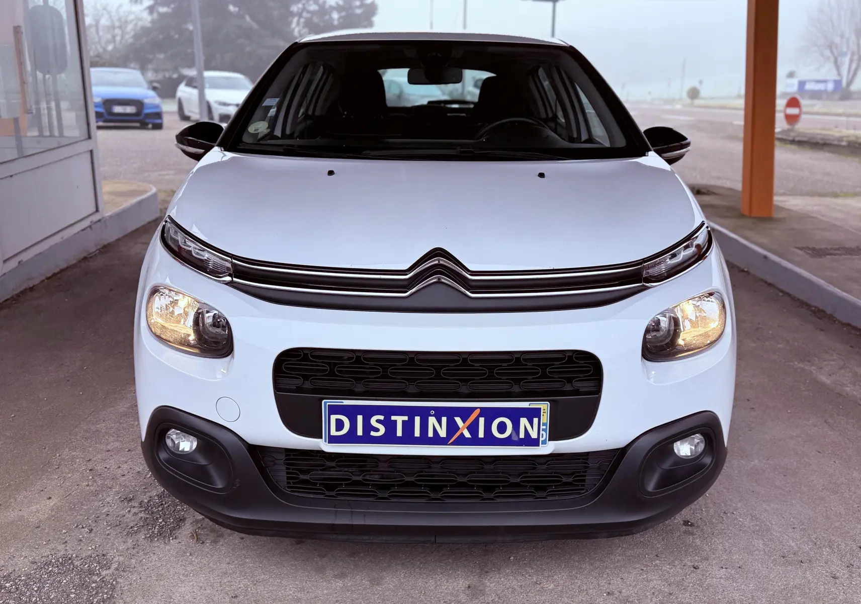 Vue avant d'une Citroën C3 Société blanche de 2019 avec phares allumés et calandre noire distinctive.