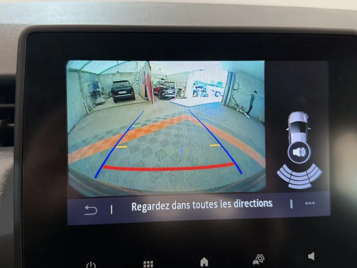 Affichage caméra de recul sur écran tactile d'une Renault Clio noire, avec guidage de trajectoire et capteurs de stationnement actifs.