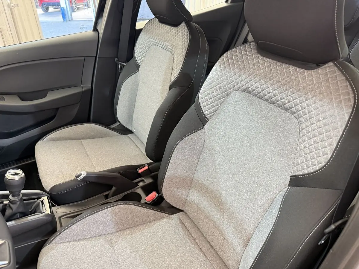 Gros plan sur les sièges avant gris et noirs de la Renault Clio Evolution Blue dCi 100 2025 avec levier de vitesse manuel.