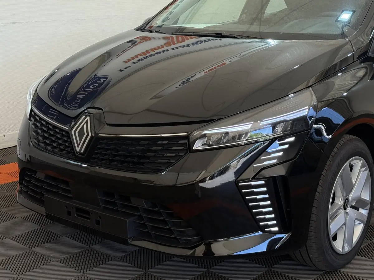 Vue 3/4 avant droit d'une Renault Clio noire 2025 avec phares LED et calandre noire brillante.