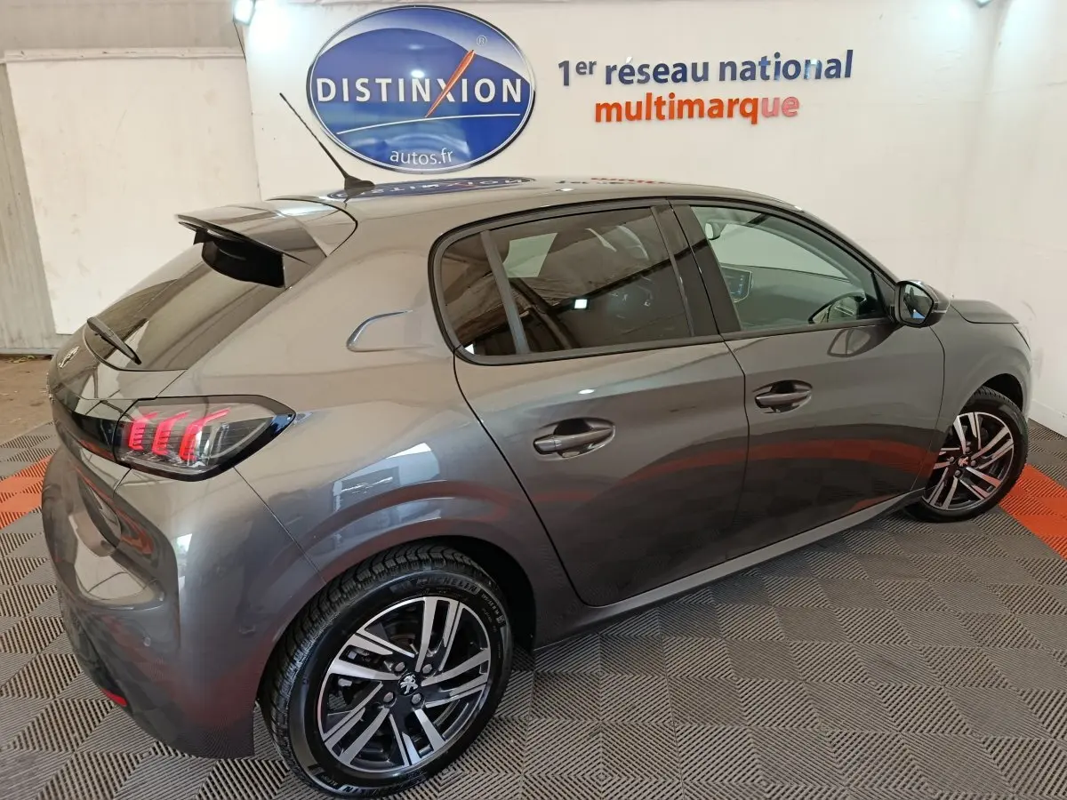Peugeot 208 BlueHDi 100 S&S Allure Business gris métallisé vue 3/4 arrière droit en intérieur showroom.