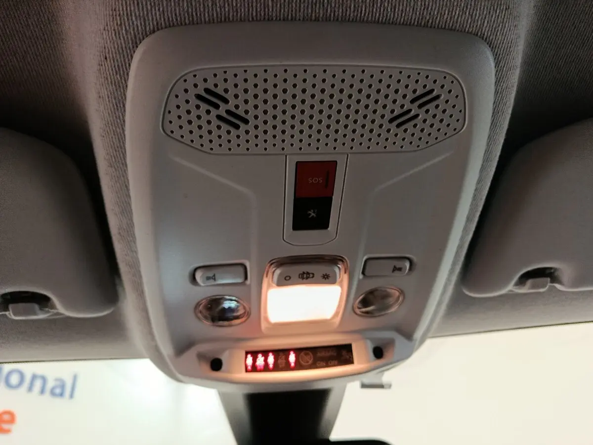 Vue intérieure en plongée sur le plafonnier gris avec bouton SOS et éclairage allumé dans une Peugeot 208 2020.