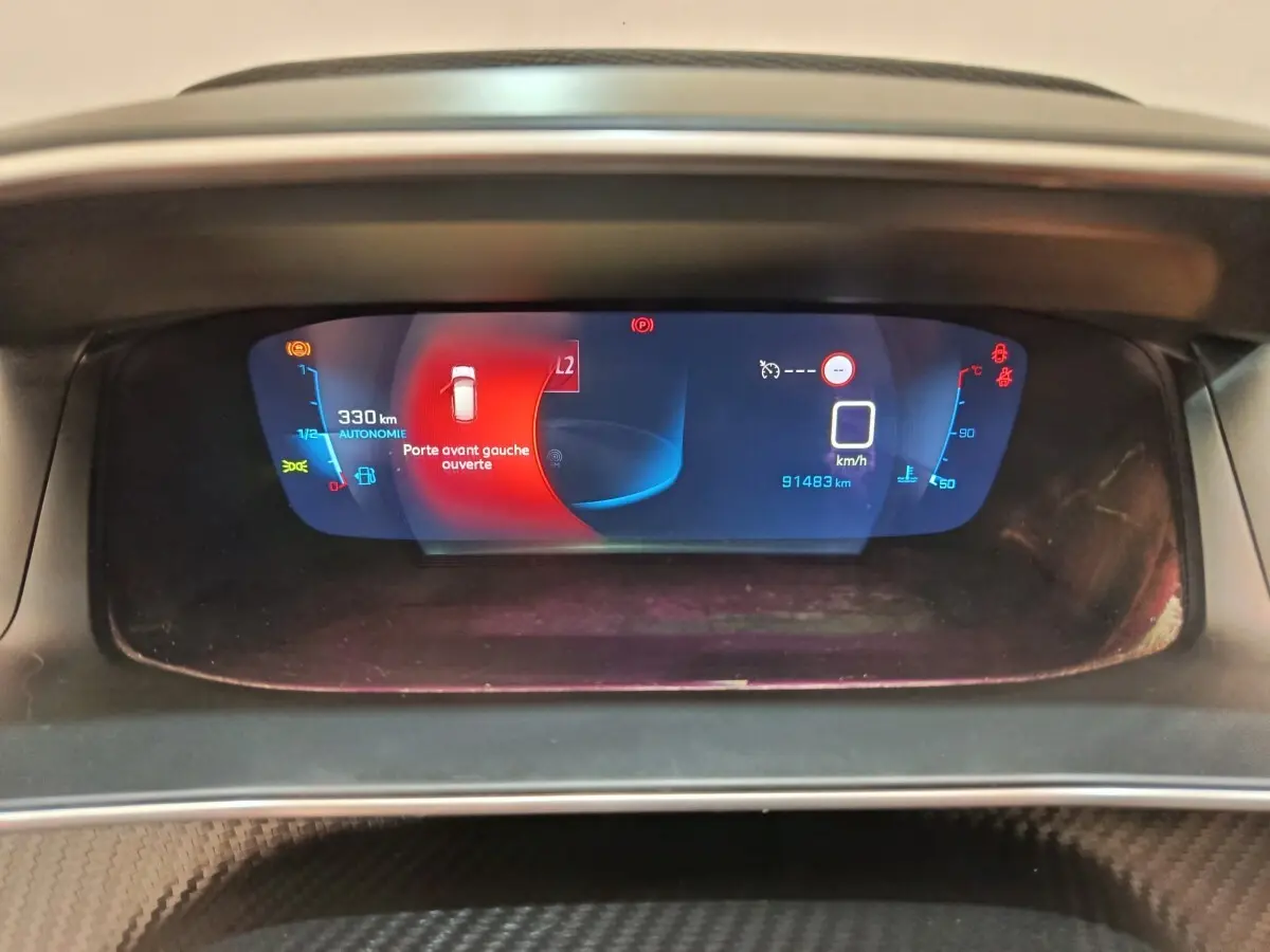 Affichage numérique du tableau de bord de la Peugeot 208 2020, indiquant porte avant gauche ouverte et autonomie 330 km.