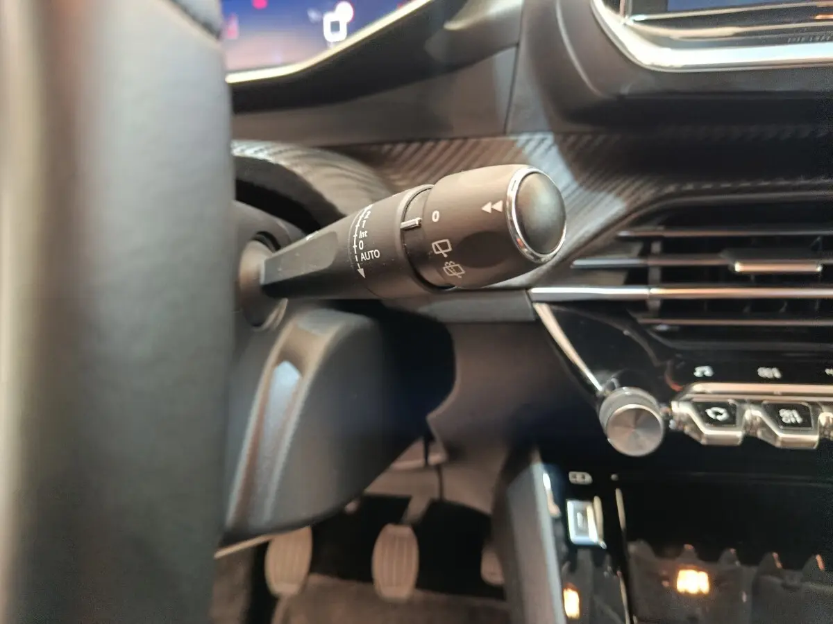 Gros plan sur la manette d’essuie-glace côté gauche du tableau de bord noir d’une Peugeot 208 2020.