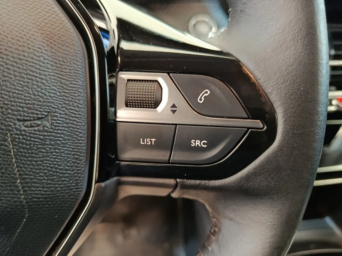 Gros plan sur les commandes gauche du volant cuir noir de la Peugeot 208 BlueHDi 100 S&S Allure Business 2020.