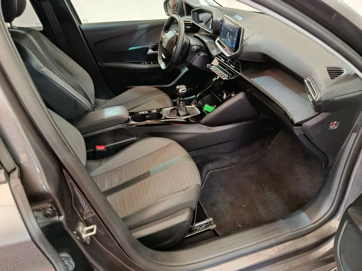 Vue intérieure côté conducteur de la Peugeot 208 2020, sièges gris, volant cuir multifonctions et écran tactile central.