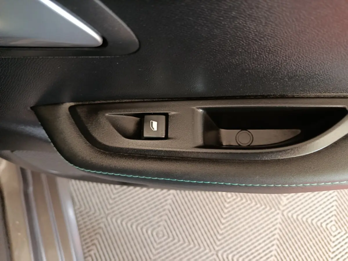 Gros plan sur la commande de lève-vitre côté conducteur de la Peugeot 208 BlueHDi 100 S&S Allure Business, intérieur noir.
