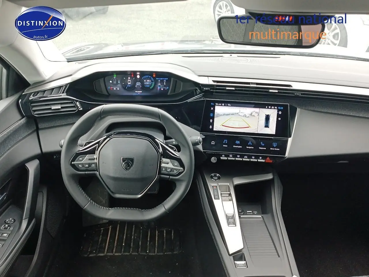 Vue intérieure avant centrée sur le volant cuir multifonction et l'écran tactile affichant la caméra de recul de la Peugeot 408 gris sélénite.
