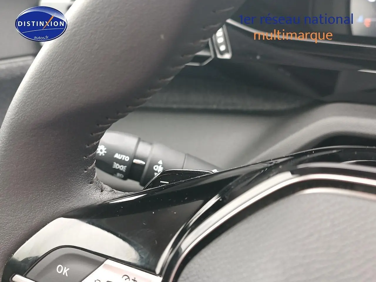 Gros plan sur le volant cuir noir multifonction d’une Peugeot 408 Hybrid 145 allure gris sélénite, avec commandes au volant visibles.