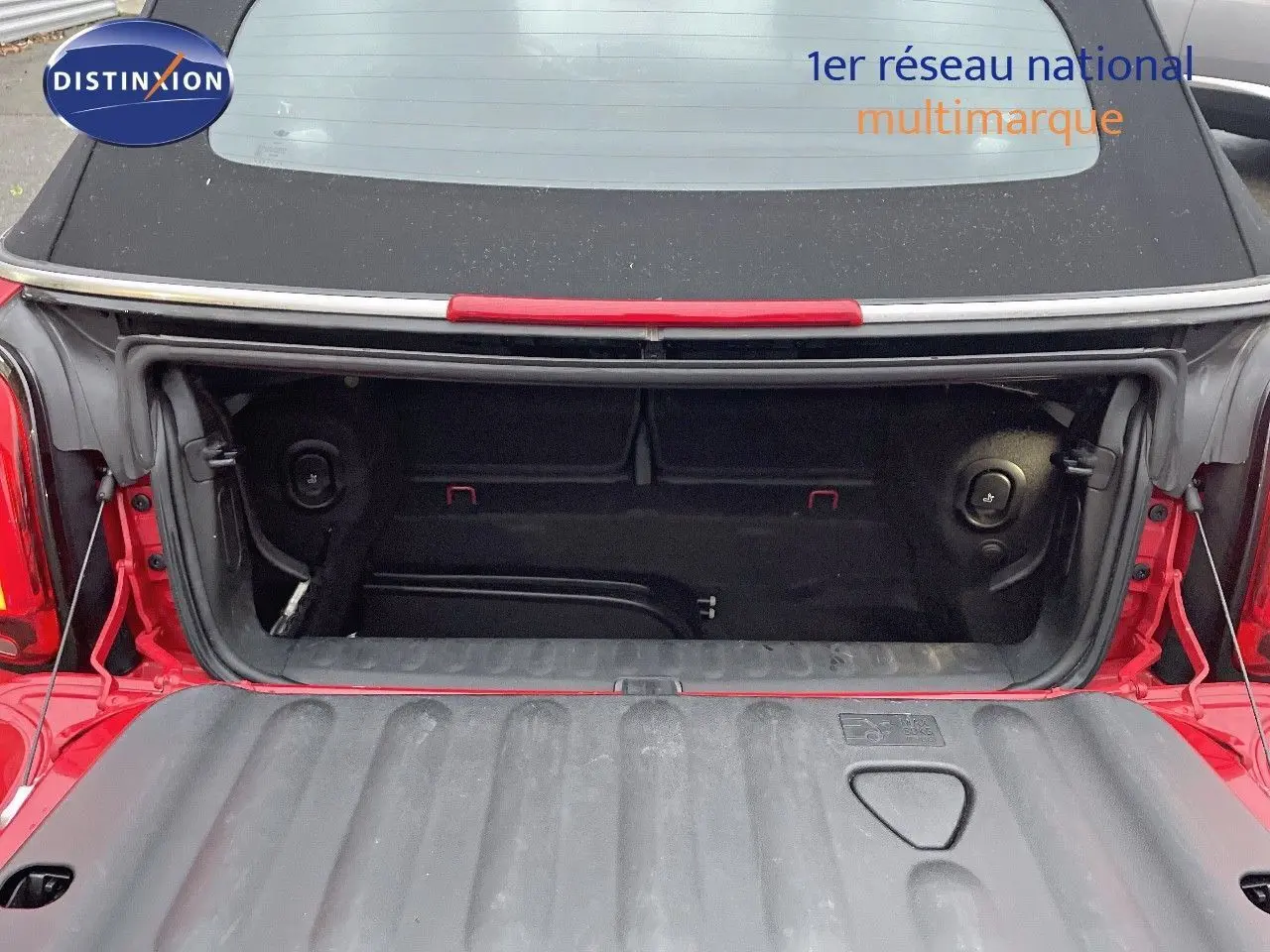 Coffre ouvert d'une MINI Cabriolet F57 rouge chili vue arrière, montrant l'espace de chargement noir.