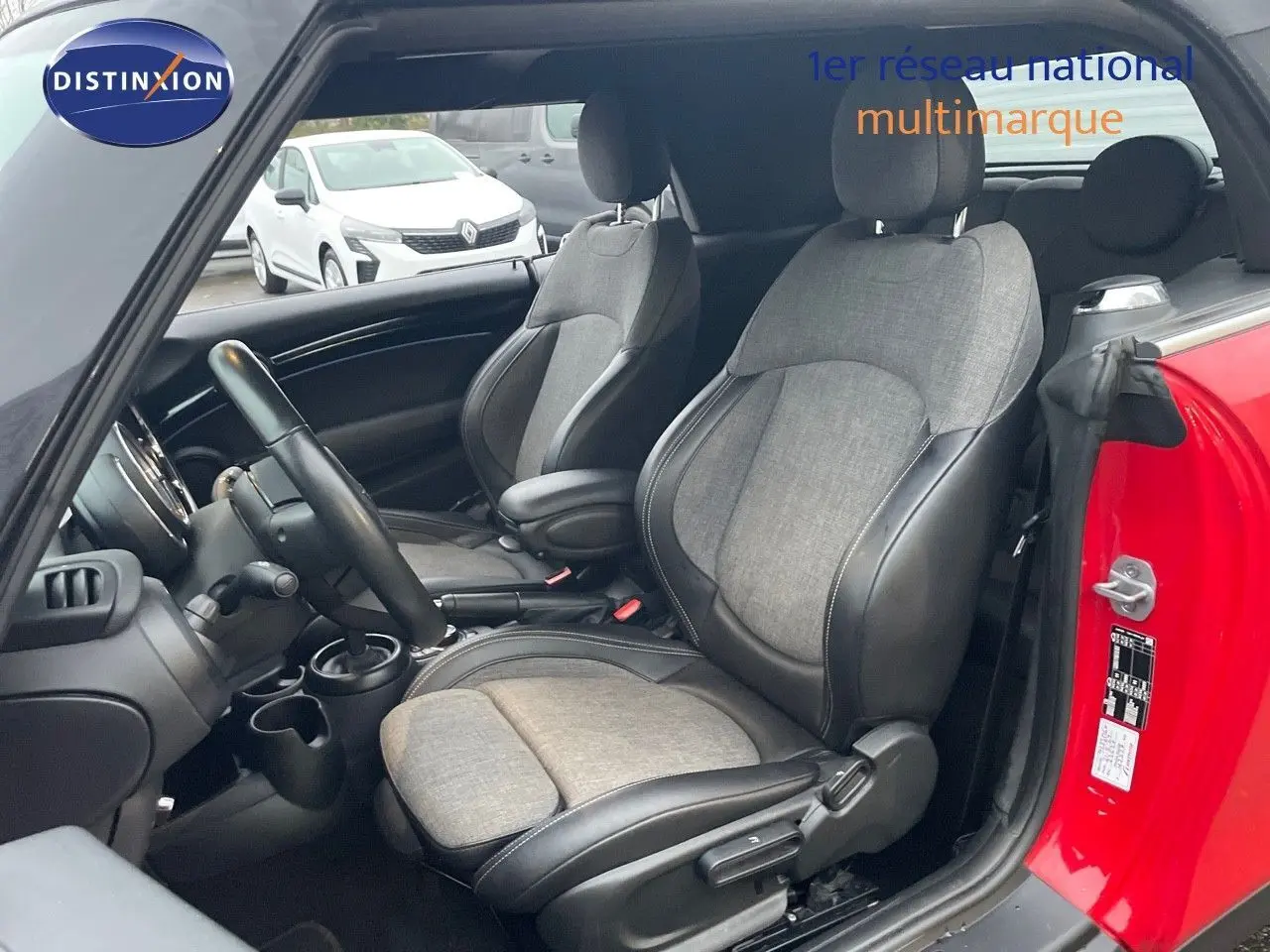 Vue intérieure côté conducteur d'une MINI Cabriolet F57 rouge chili, sièges bi-matière gris et noir visibles.