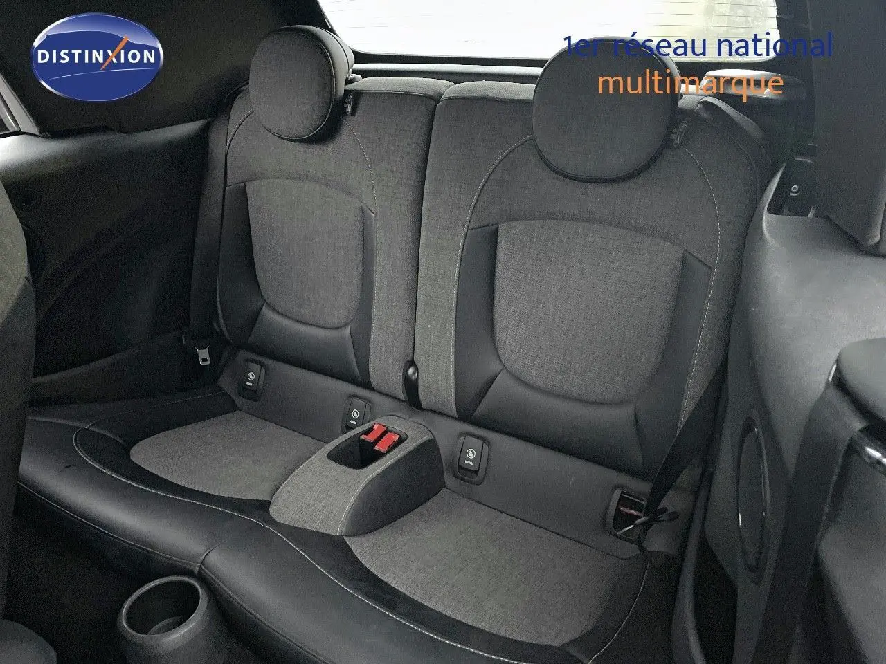 Vue intérieure arrière montrant les sièges arrière gris et noirs d'une MINI Cabriolet F57 rouge chili 2023.