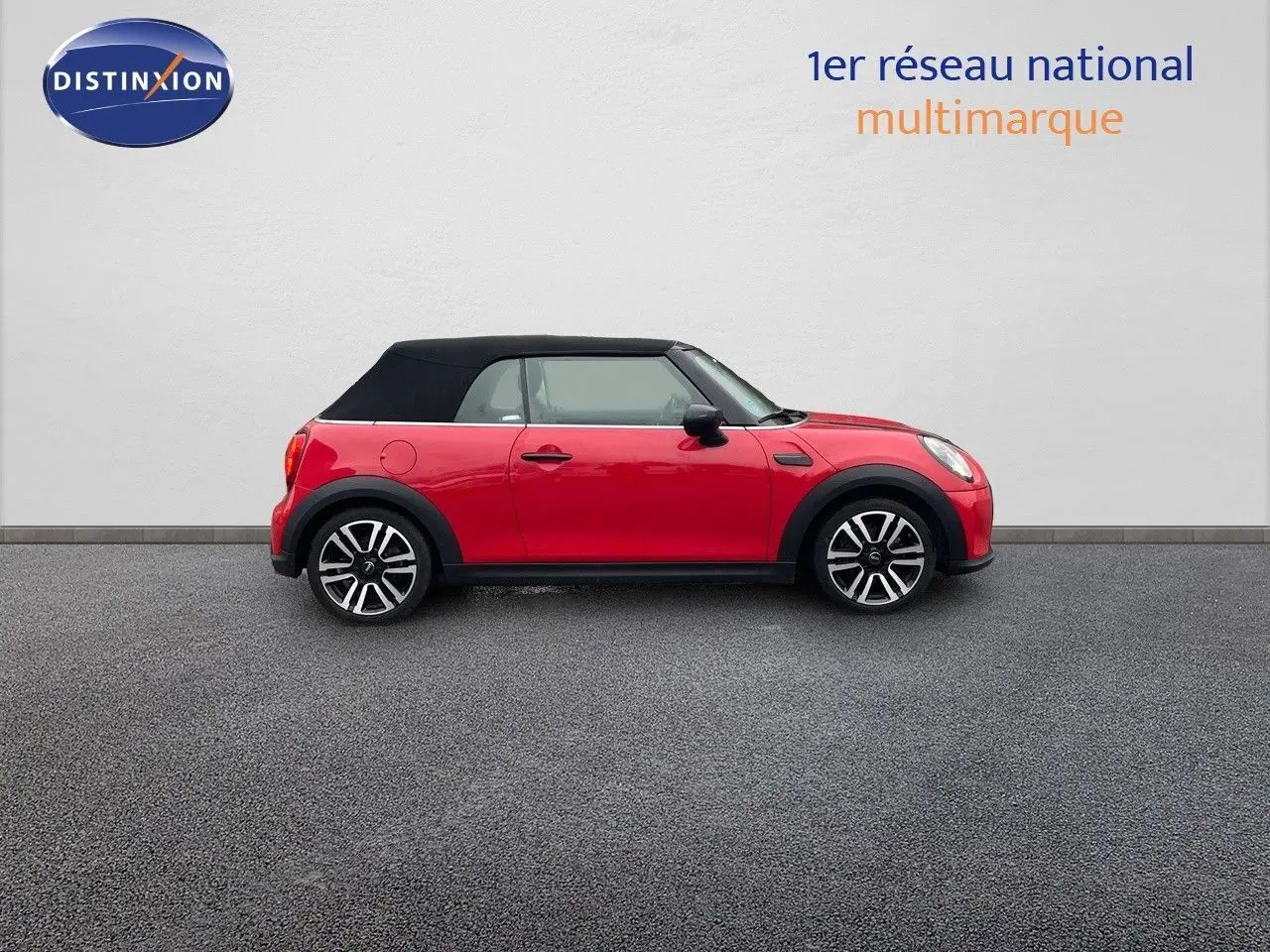 Profil gauche d'une MINI Cabriolet F57 rouge chili 2023 avec capote noire et jantes bi-ton élégantes.