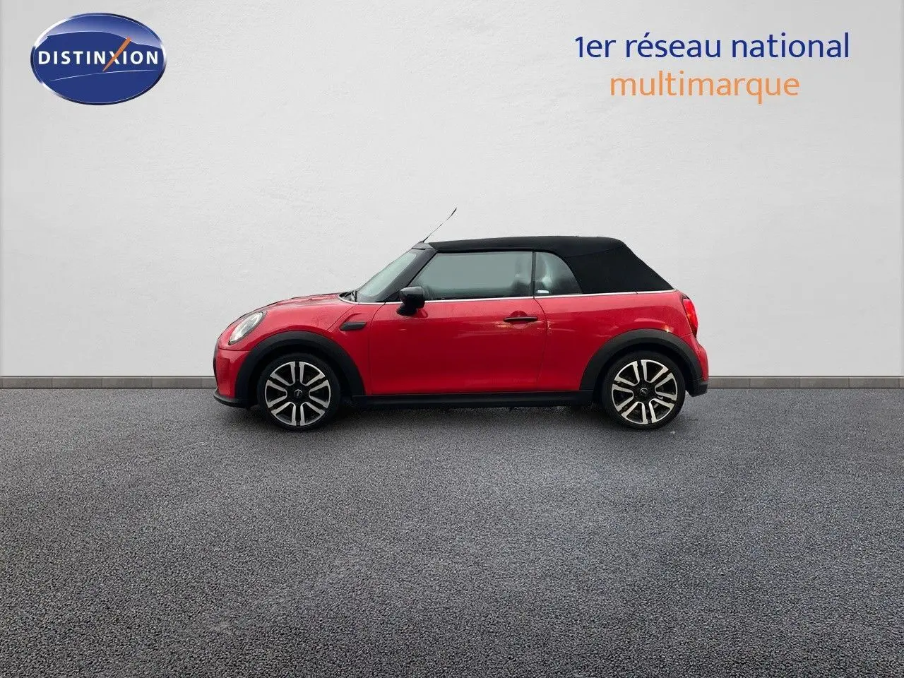 Profil côté gauche d'une MINI Cabriolet F57 rouge chili avec toit noir fermé sur fond neutre.