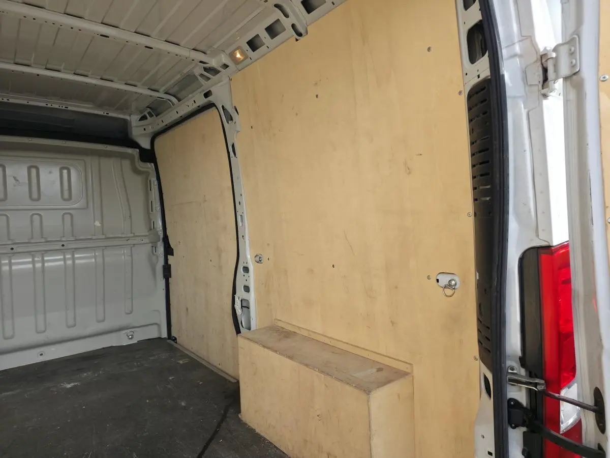Intérieur du fourgon Opel Movano blanc vu de l'arrière, avec panneaux latéraux et plancher en bois clair.