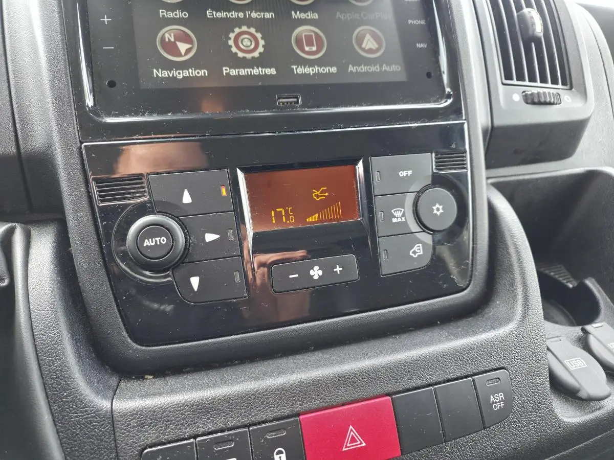 Gros plan sur la console centrale noire de l'Opel Movano Fourgon 2022, affichant la climatisation et l'écran tactile.