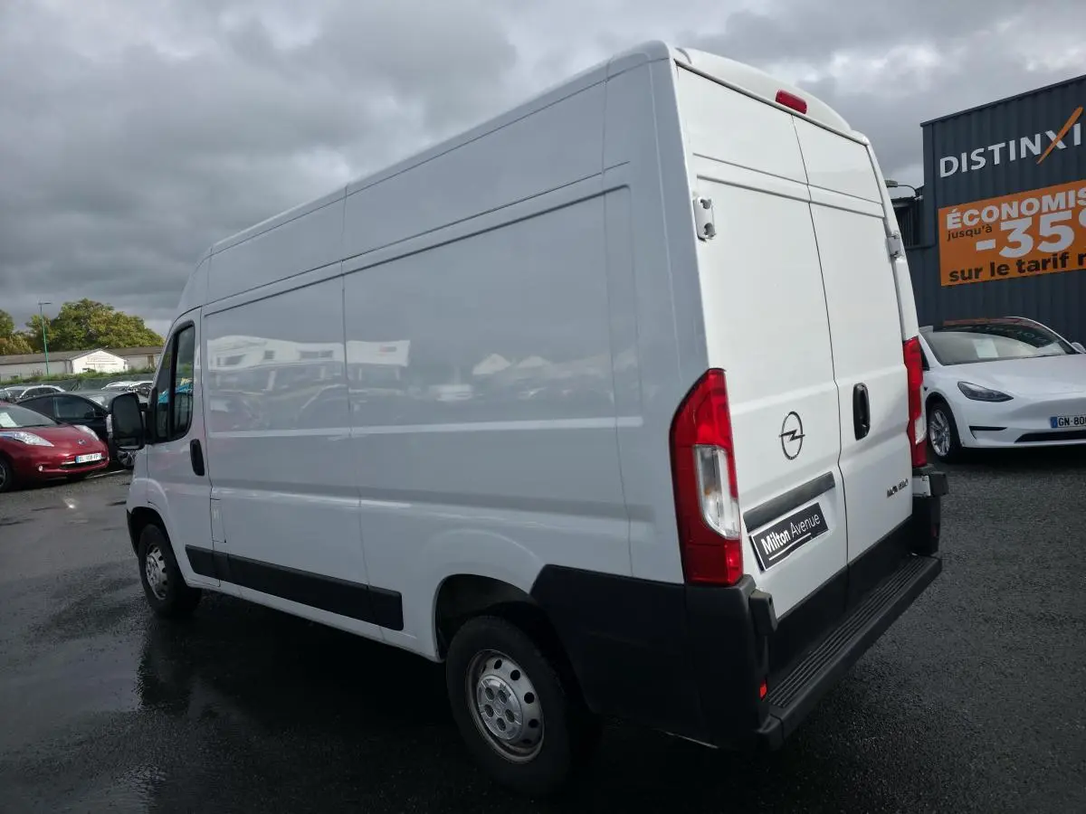 Vue 3/4 arrière droite d'un Opel Movano Fourgon blanc avec portes arrière battantes et panneau latéral lisse.