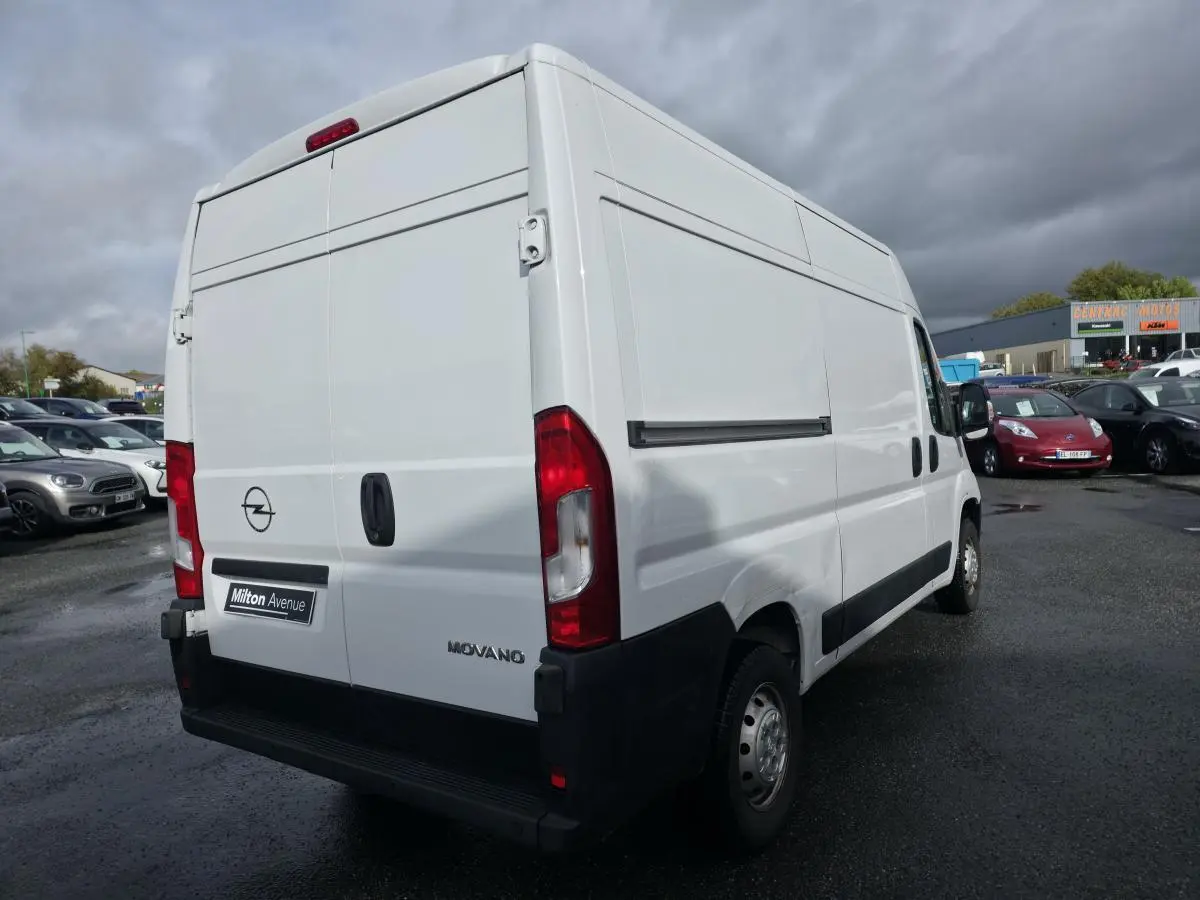 Vue 3/4 arrière droite d'un fourgon blanc Opel Movano avec portes battantes et panneaux latéraux lisses.