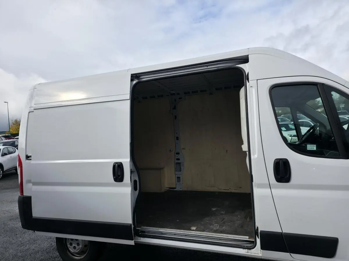 Vue latérale droite d'un Opel Movano Fourgon blanc avec porte coulissante ouverte montrant l'intérieur bois.