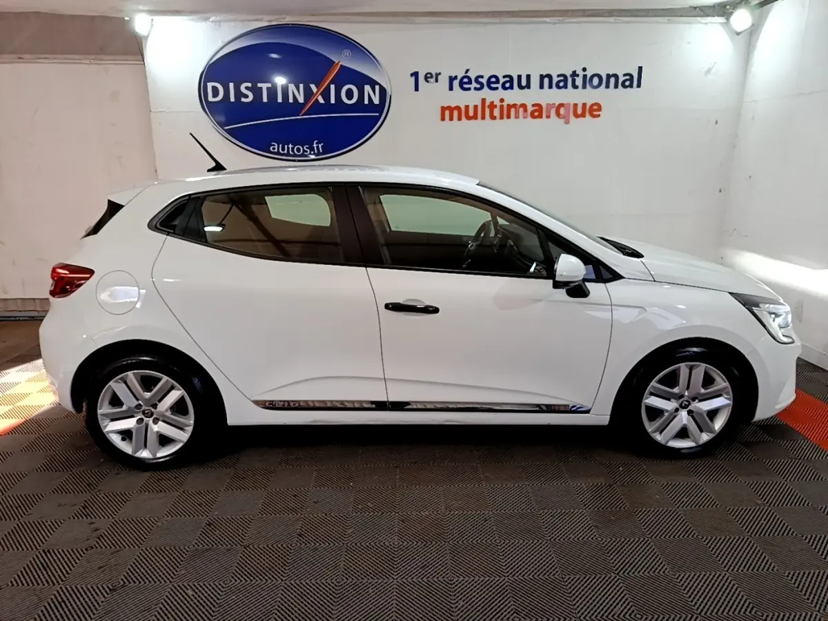 Profil droit d'une Renault Clio Business blanche 2021, avec jantes alliage et vitres teintées, en intérieur showroom.