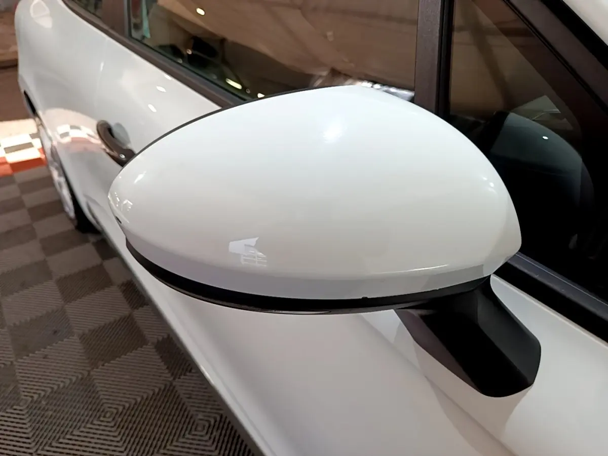 Rétroviseur droit blanc en gros plan sur Renault Clio Business 2021, avec portière et vitre partiellement visibles.