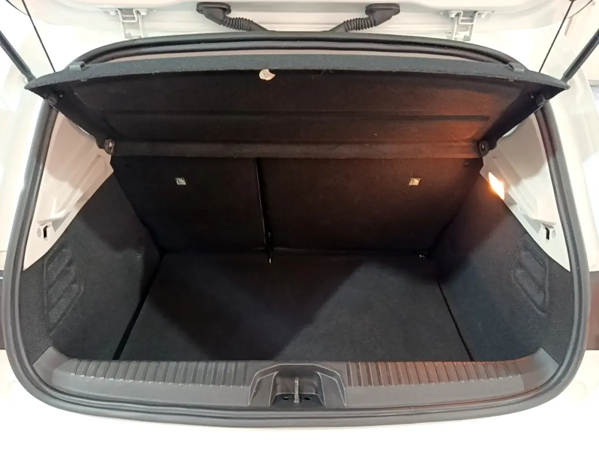 Coffre ouvert vu de face d’une Renault Clio Business blanche, montrant l’espace de chargement vide et la lumière intérieure.