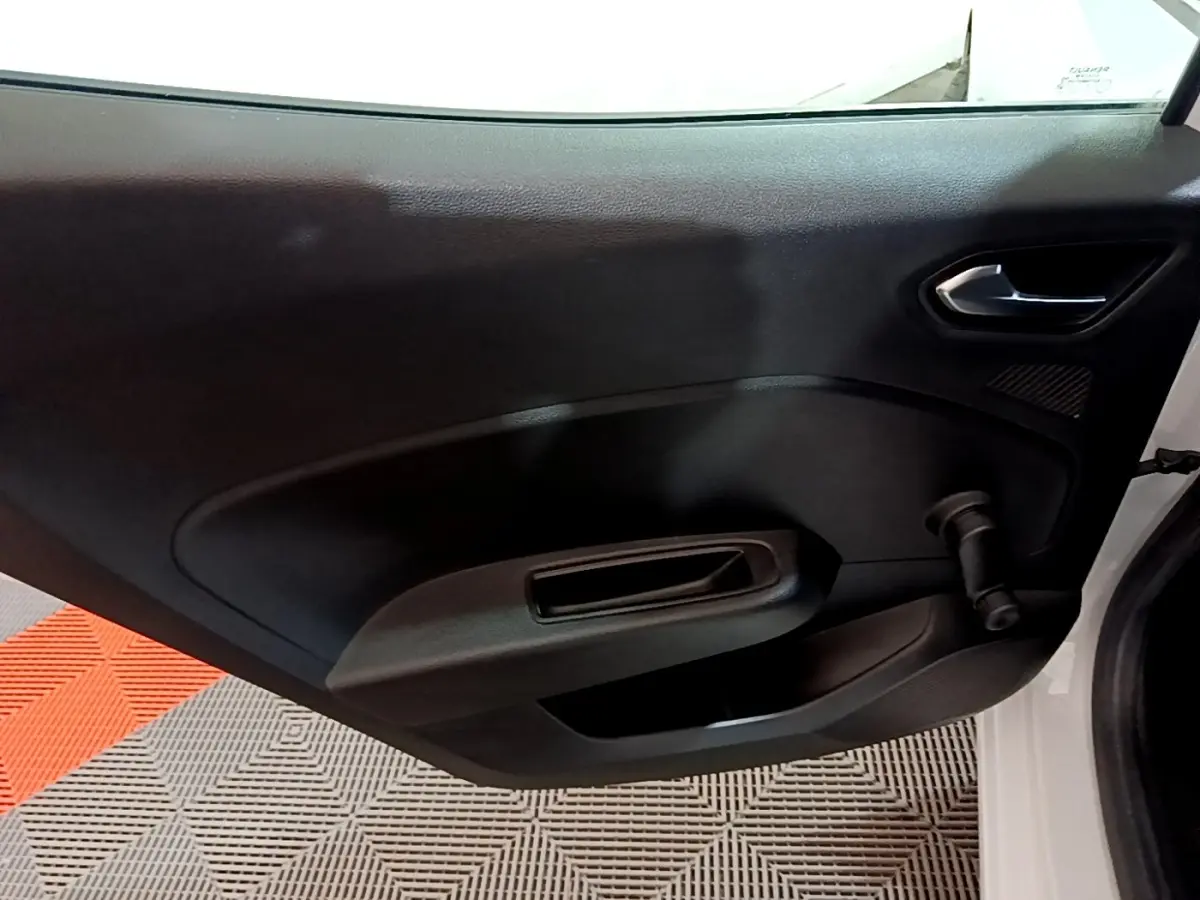 Vue intérieure de la porte arrière droite noire d’une Renault Clio Business blanche, avec poignée et manivelle de vitre.