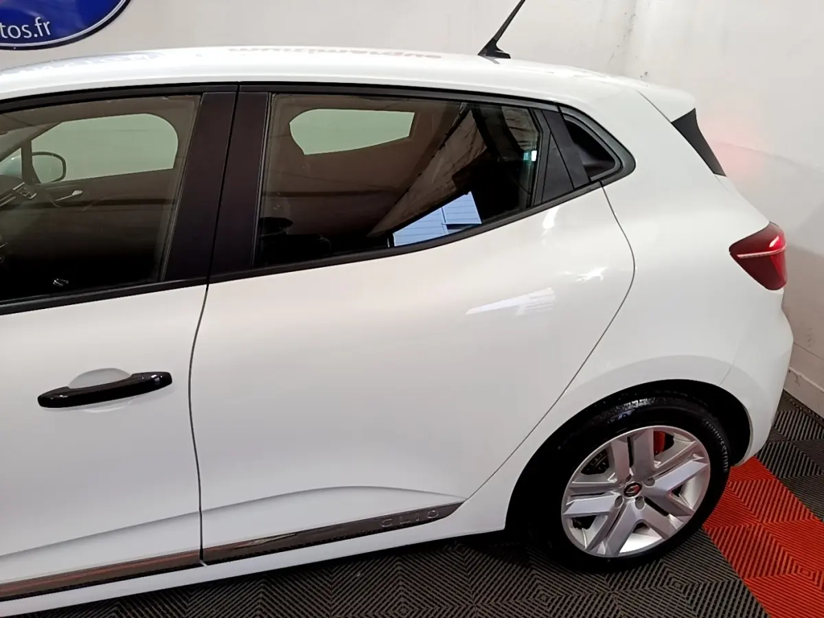 Vue latérale côté droit d'une Renault Clio Business blanche, avec jantes alliage et poignées noires contrastantes.