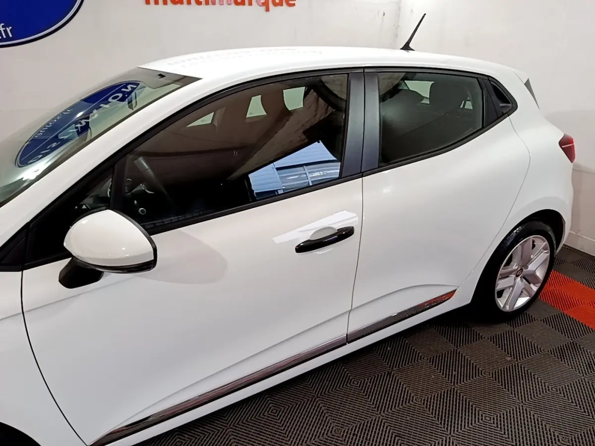 Profil côté gauche d'une Renault Clio Business blanche, mettant en valeur la ligne fluide et les jantes alliage.