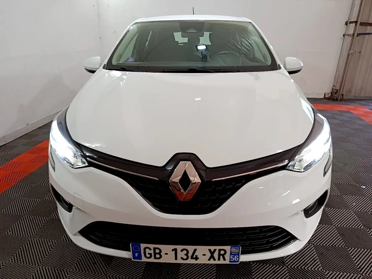 Vue avant d'une Renault Clio Business blanche avec phares LED allumés dans un garage.