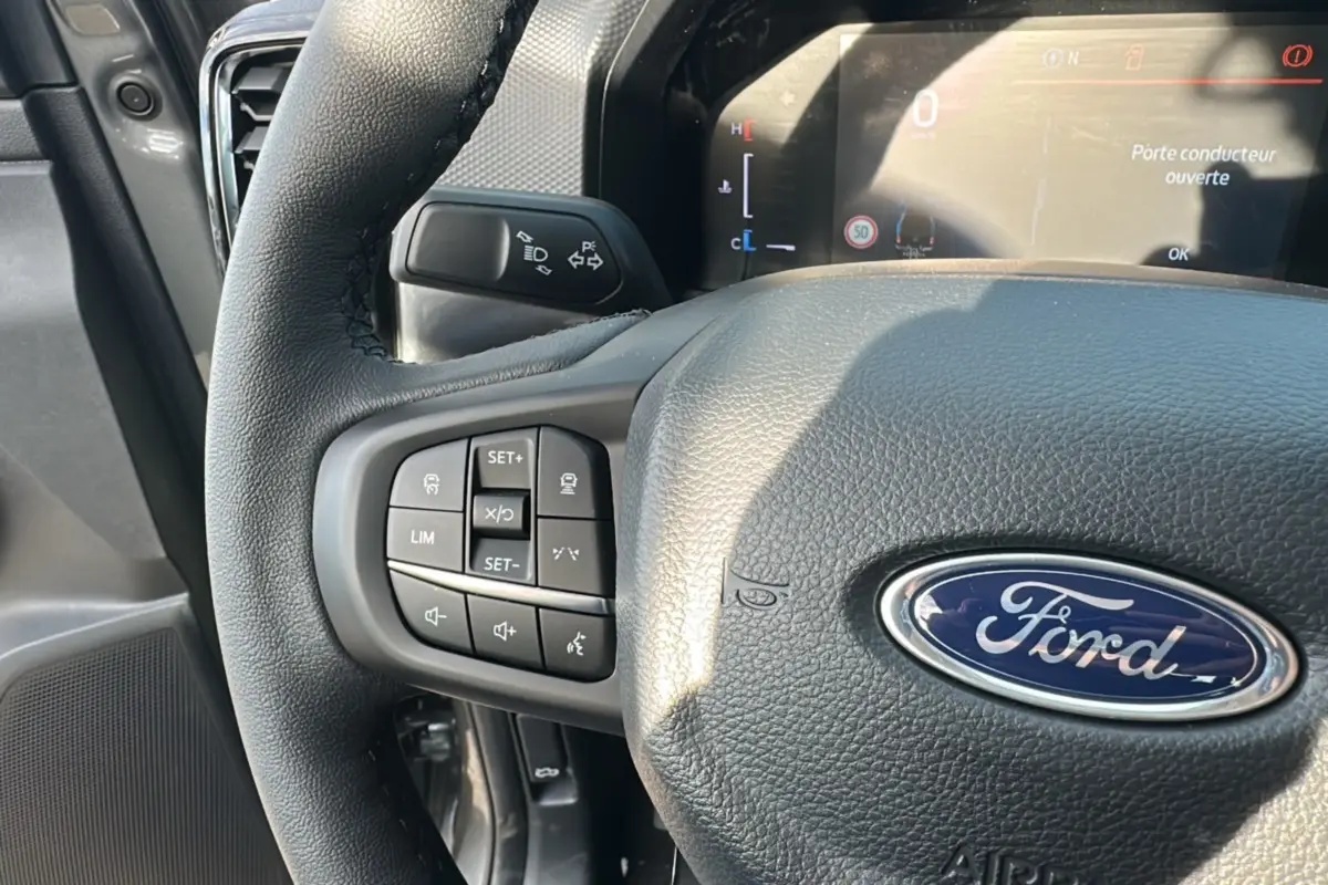 Vue rapprochée du volant cuir noir du Ford Ranger 2026 avec commandes multifonctions et tableau de bord digital.