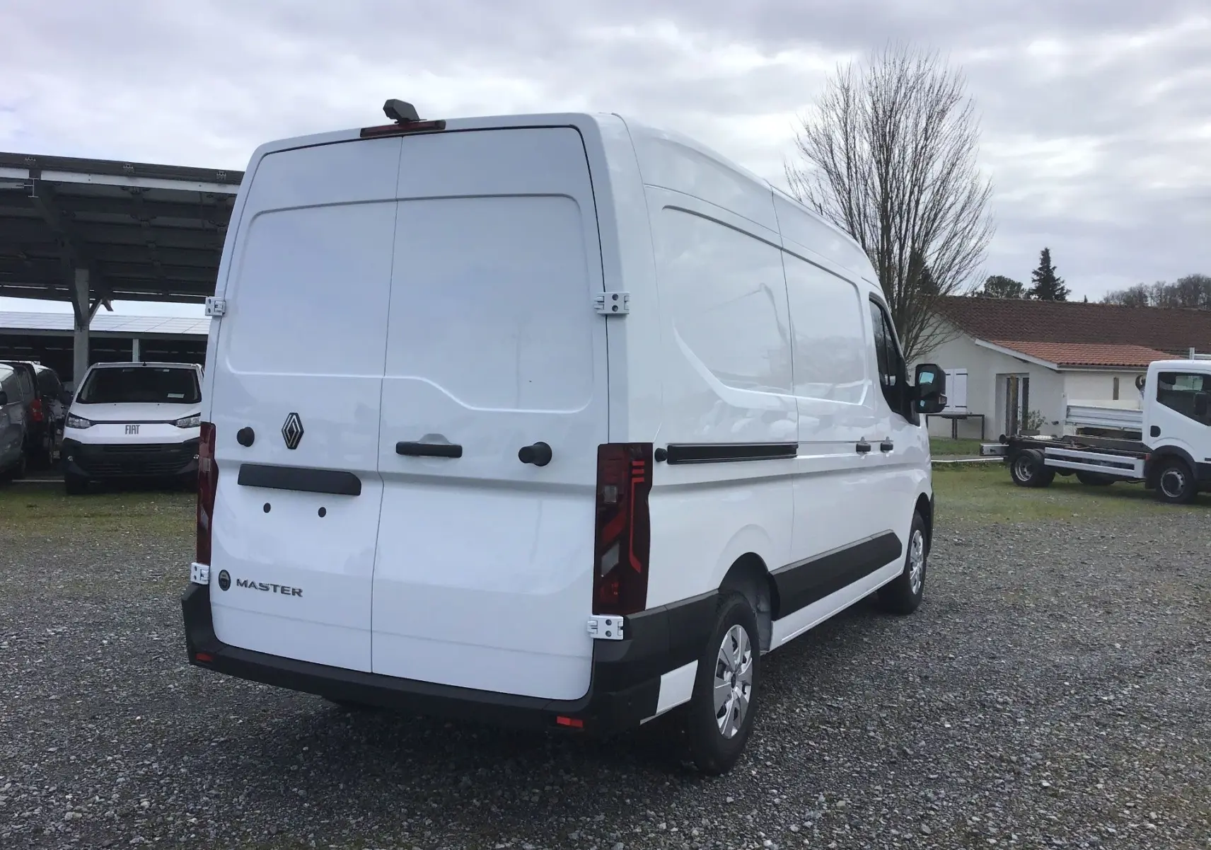Vue 3/4 arrière droite d’un Renault Master blanc 2026, fourgon utilitaire avec portes arrière fermées sur un parking extérieur.